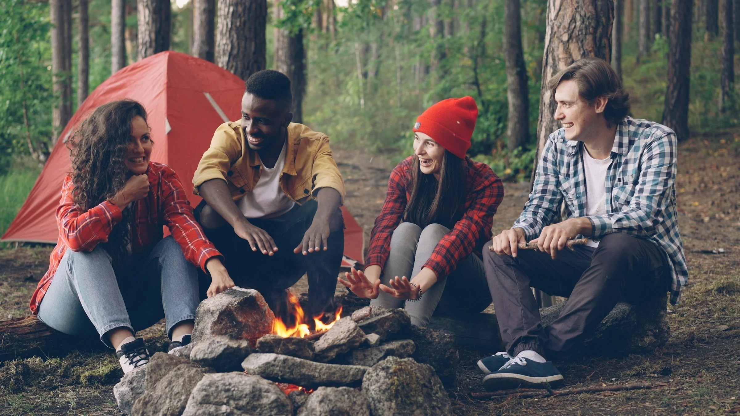 Friends sitting around a campfire at a forest campsite